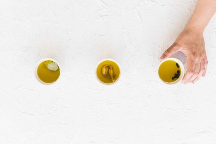 hand-holding-bowl-oil-white-textured-backdrop